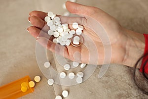 Many white pills and wedding ring lying on womans hand closeup