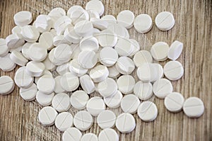 Many white pills on a wooden background. Close-up.