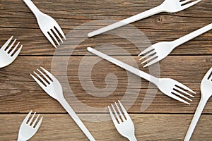 Many white plastic forks on a grey wooden background