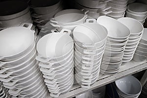 Many of white plate and bowl on shelves in kitchenware shop.