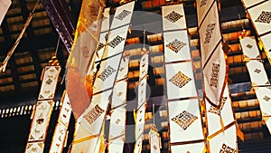 Many white ribbons with gold ornaments flutter in the wind in a Buddhist temple in Southeast Asia. Buddhist symbols Tung