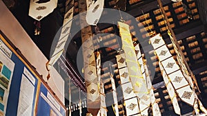 Many white ribbons with gold ornaments flutter in the wind in a Buddhist temple in Southeast Asia. Buddhist symbols Tung