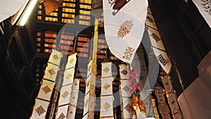 Many white ribbons with gold ornaments flutter in the wind in a Buddhist temple in Southeast Asia. Buddhist symbols Tung
