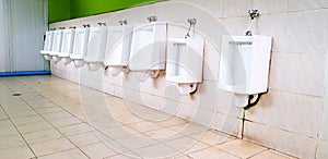 Many white urinal on white dirty wall in men public toilet or rest room