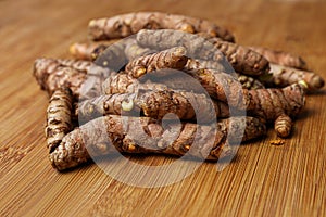 Many whole turmeric roots on wooden table