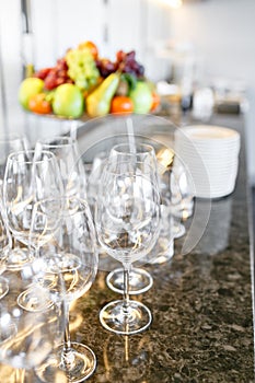 Many wineglasses. Breakfast in restaurant of hotel. Plate with fruits and berries on a smorgasbord in the background. Bar