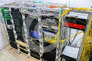 Many wires intertwine on top of server cabinets. Racks with Internet telecommunications equipment are in the server room. Modern