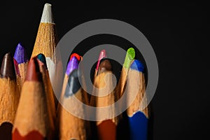 Many wooden crayons that have been used in the dark background are macro images