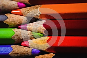 Many wooden crayons that have been used in the dark background are macro images