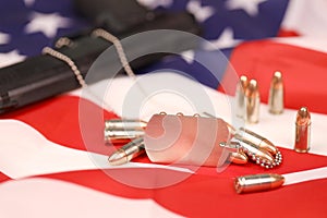 Many yellow 9mm bullets and gun with dogtags on United States flag. Concept of duty and service in US army forces