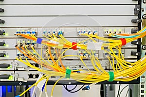 Many yellow optical wires are connected to the central router in the data center server room. Powerful network equipment of a