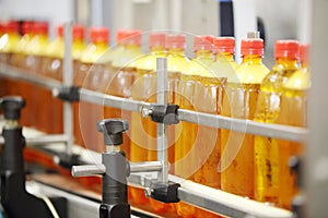 Many yellow plastic bottles with fresh beer go on conveyor