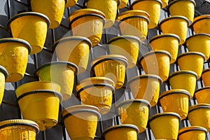 Many yellow plastic pots for plants and seedlings hanging in a row, spring gardening preparation and planting concept