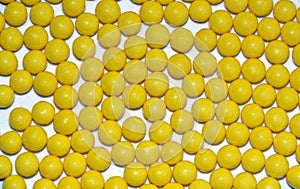 Many yellow round dragees of ascorbic acid vitamin C isolated on white background