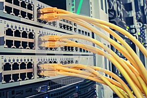 Many yellow utp wires connect to internet switches. Communication equipment is in the server room of the data center. Network
