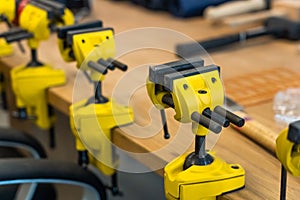 Many Yellow Vises are Set on the Work Bench at the School.