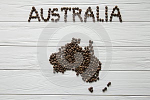 Map of the Australia made of roasted coffee beans laying on white wooden textured background