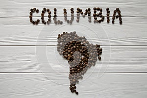 Map of the Columbia made of roasted coffee beans laying on white wooden textured background