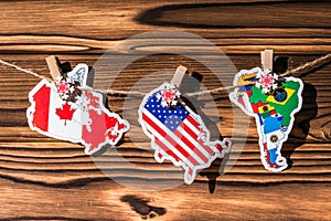 Map flag of North, South America, Canada hanging on a rope on wooden clothespins. Rustic Christmas decoration.