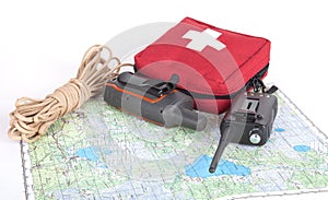 Map, gps navigator, portable radio, rope and first aid kit on a