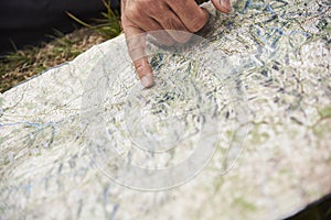 A map on the ground, one hand points to a place. Concept: orientation in nature