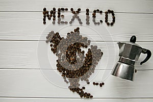 Map of the Mexico made of roasted coffee beans laying on white wooden textured background with coffee maker