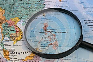 Map of the Philippines through magnifying glass on a world map.