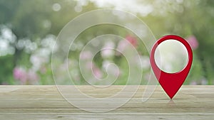 Map pin point location button on wooden table over blur pink flower and tree in garden, Map pointer navigation concept