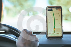 Map on smartphone of car dashboard. Mobile phone with gps or glonass navigation. Driver hand holds steering wheel