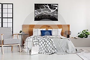 Map on white wall above wooden headboard in simple bedroom interior