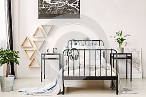 Map on white wall of fashionable kid`s bedroom with industrial single bed and nightstand with clock and cup