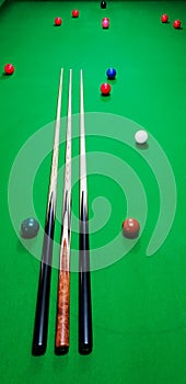 Maple and ebony cues on a snooker table with balls