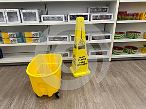 Mop bucket and caution wet floor sign warning customers at a Kohls Department Store