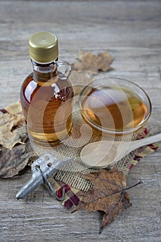 Maple syrup bottle and glass container on wood table photo