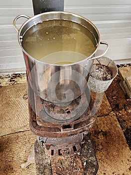 Maple syrup water boilling pot on wood stove in maplehouse. Maple farming. Tools and equipment.