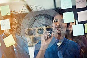 Mapping out their opportunities for success. a group of businesspeople brainstorming with notes on a glass wall in an