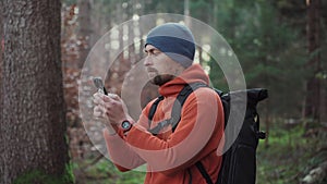 Maps outdoors while hiking. Hiker use smartphone to navigation in forest via app cartography. Trekking routes by