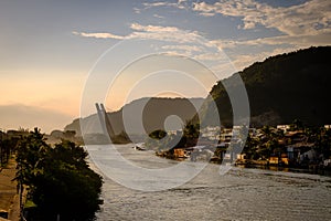 Marapendi Lagoon seen from above with houses on the hill during sunset, golden light. Jet skis are riding on the lake. Barra da Ti