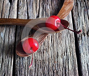 Maraschino cherry vibrant on wooden spoon and old table background