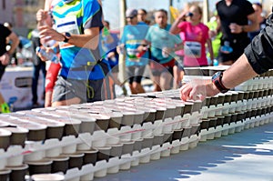 Marathon running race, runners on road, isotonic drinks on refreshment point