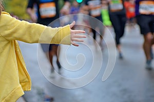 Marathon running race,runners support on road race, child`s hand giving highfive, kid supporting athletes who run