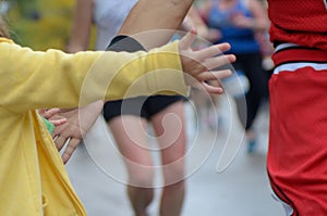 Marathon running race,runners support on road race, child`s hand giving highfive, kid supporting athletes who run