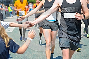 Marathon running race,runners support on road race, child`s hand giving highfive, kid supporting athletes who run