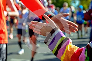 Marathon running race, support runners on road, child's hand giving highfive