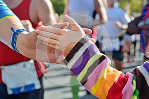 Marathon running race, supporting runners on road, child hand giving highfive, sport event