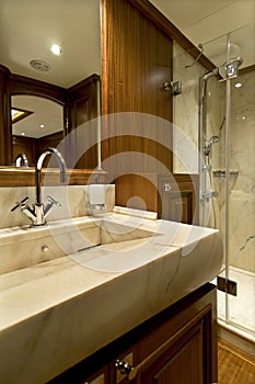 A marble bathroom, a mirror and a shower in a luxury yacht.