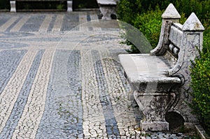 Marble bench in park. Road made with traditional portugal technique of pavement