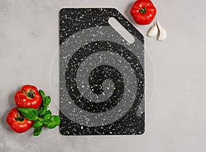 Marble black cutting board ripe tomatoes basil garlic gray background. Ingredients fresh vegetables