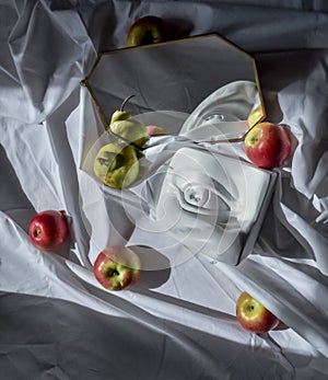 Marble copy eye of david reflected in a mirror in a frame against a background of white drapery fabric with folds with fruits