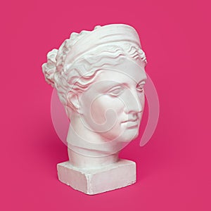 Marble head of young woman, ancient Greek goddess bust isolated on pink background